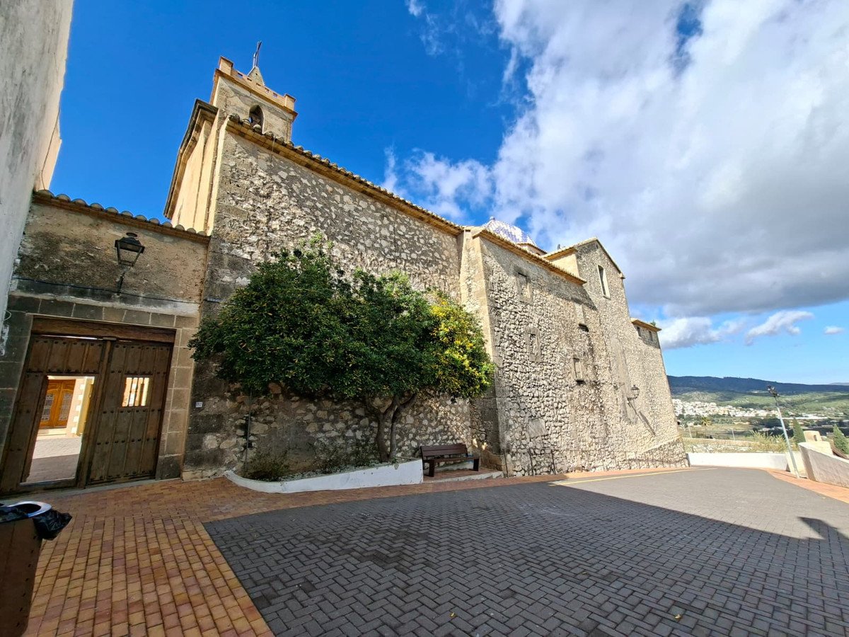 Stone building with patio, tree, bench, and mountain view under blue sky