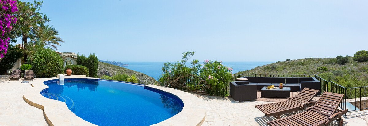 Curved infinity pool with loungers overlooking the sea and lush greenery