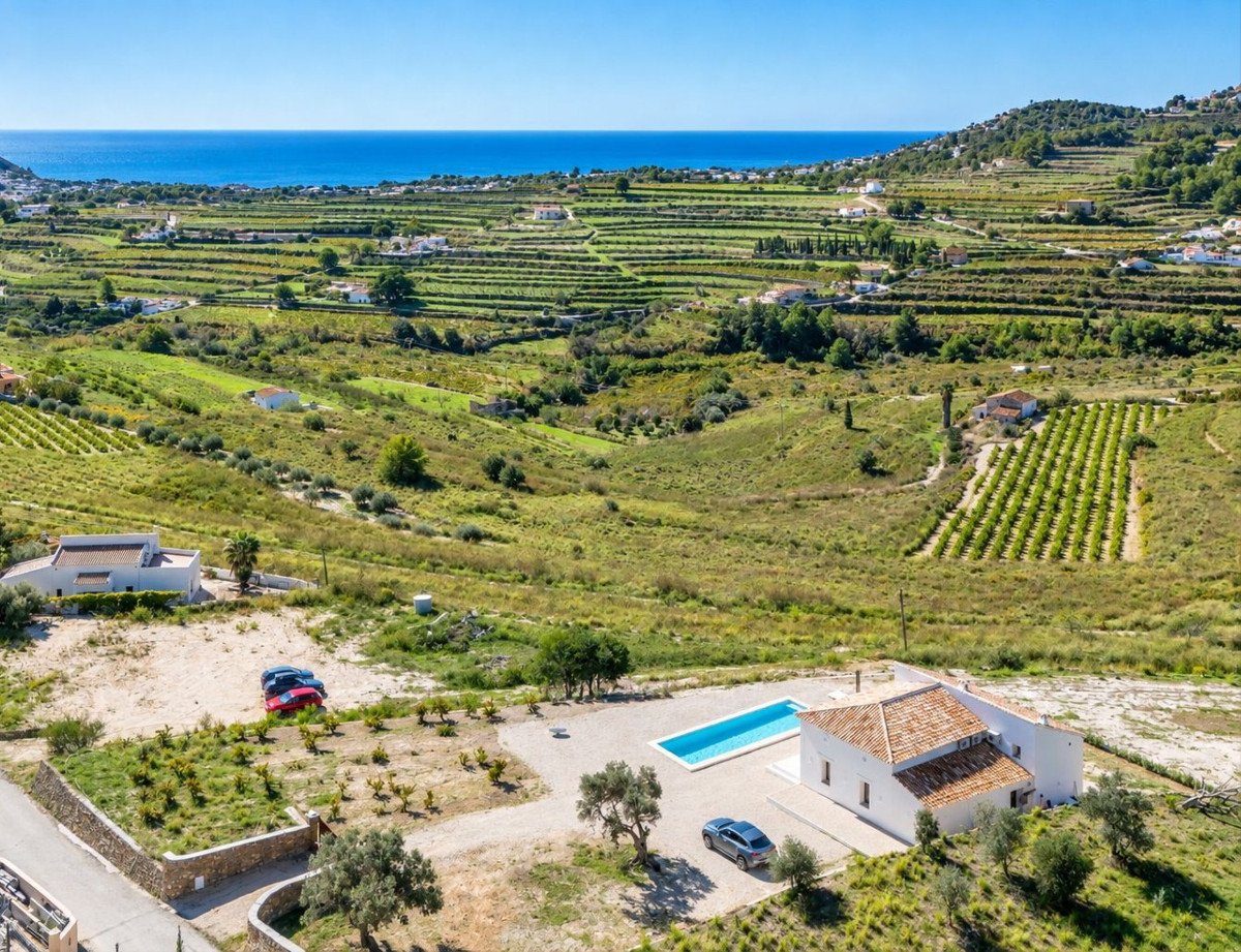 Aerial view of a villa with a swimming pool overlooking terraced fields and the sea.