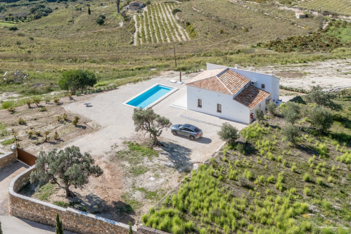 Aerial view of a white rural house with swimming pool and surrounding landscape