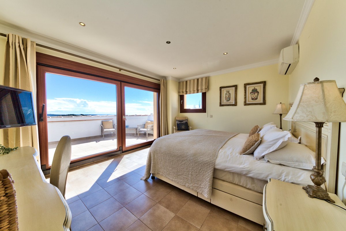 Bedroom with a large bed, access to a terrace with sea view, and a TV.