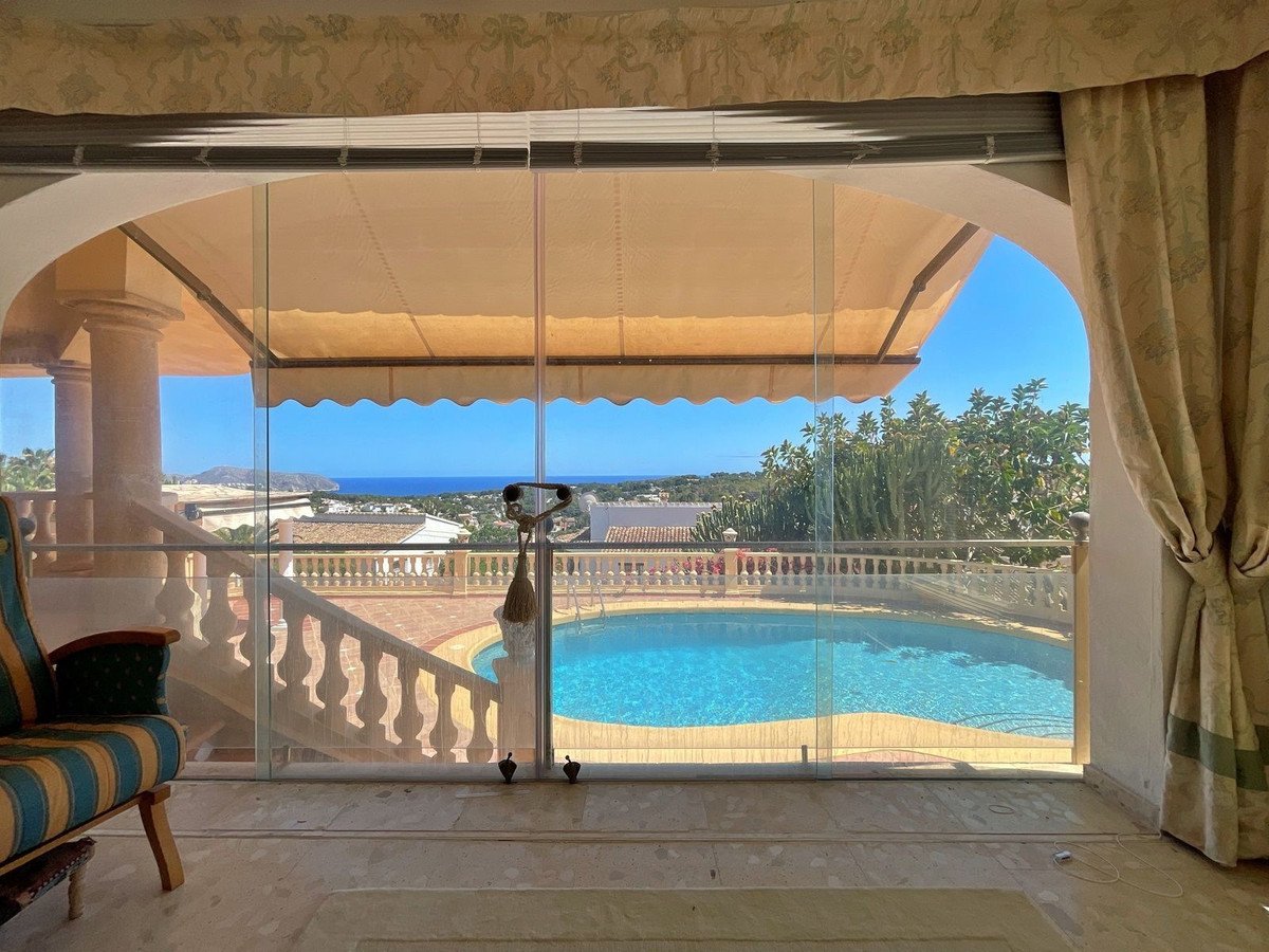 Living room with sliding glass doors opening to a pool and sea view