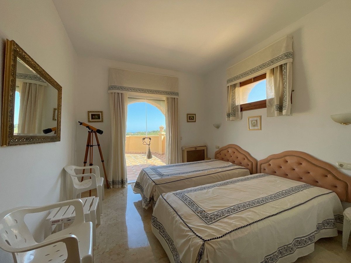 Twin bedroom with ocean view, arched door to balcony, telescope, and white furniture