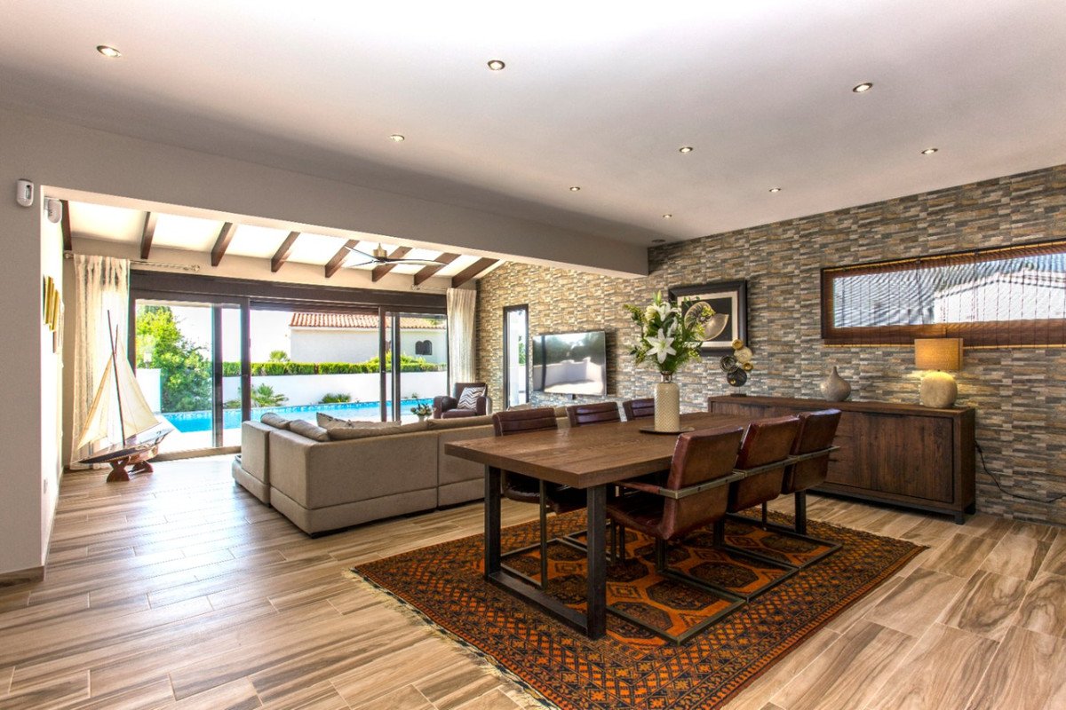 Spacious living and dining area with modern furniture, leading to a terrace with a swimming pool.
