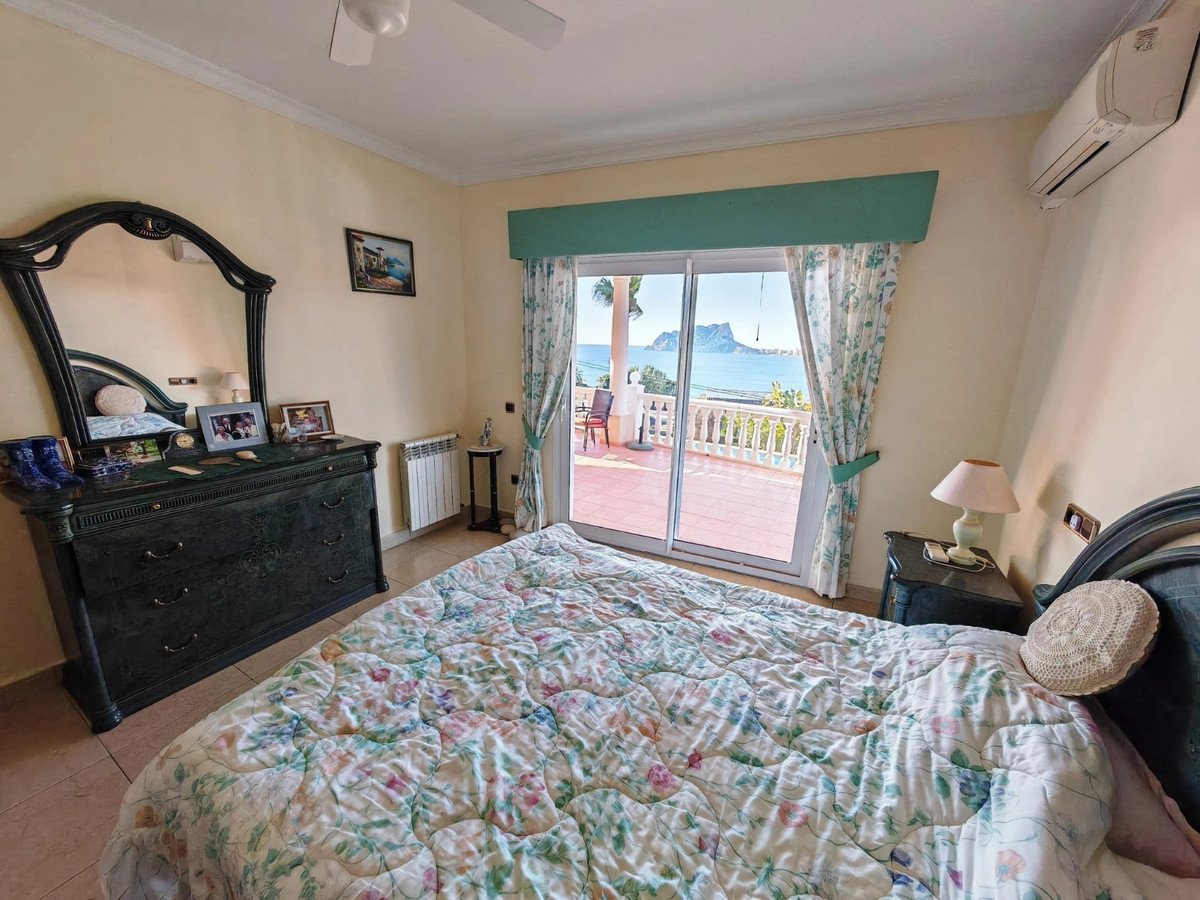 Bedroom with a sea view, balcony access, dresser, and a comfortable bed.
