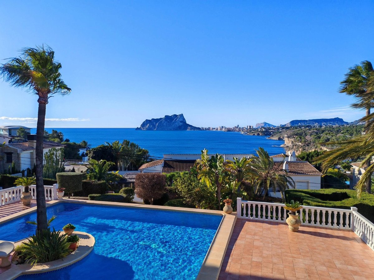 A spacious terrace with a swimming pool and palm trees, offering stunning sea and coastal views under a clear blue sky.