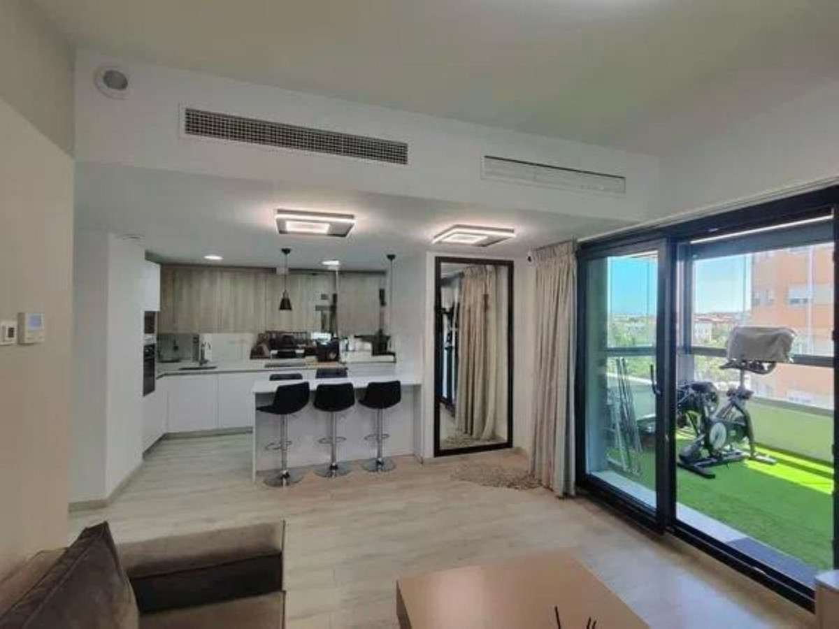 Modern appartement met open keuken, woonkamer en balkon met fitnessapparatuur.