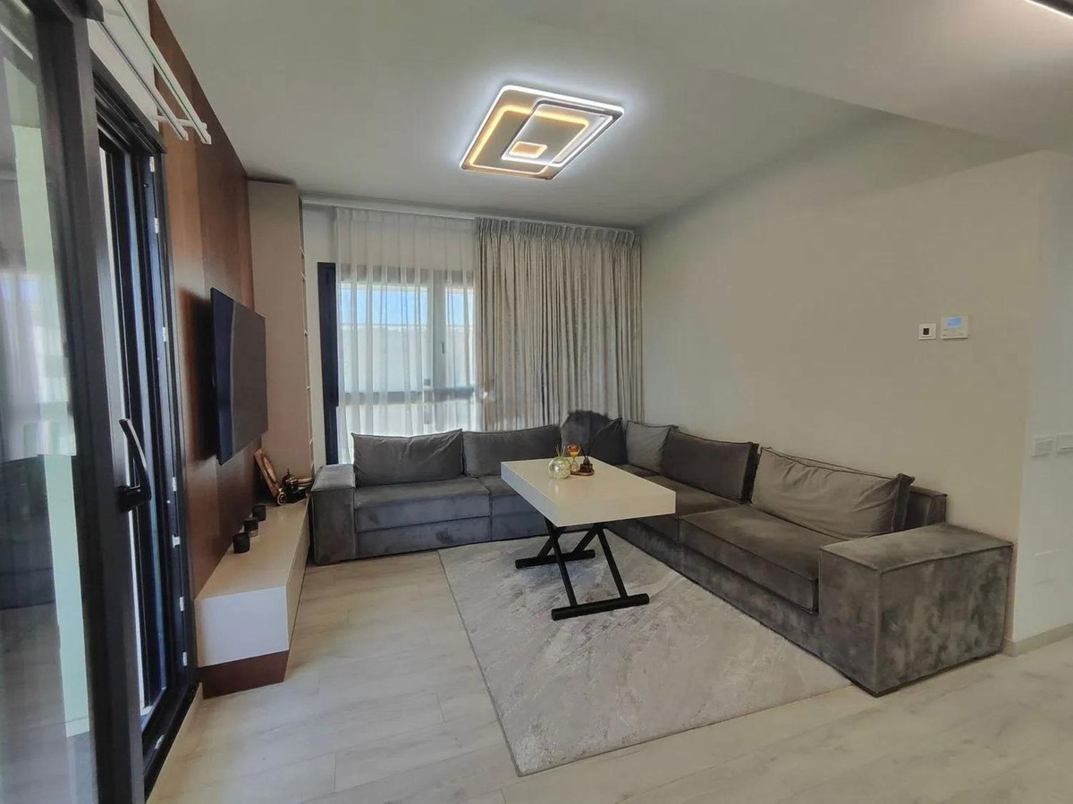 Moderne woonkamer met grijze hoekbank, witte tafel en lichte vloer.