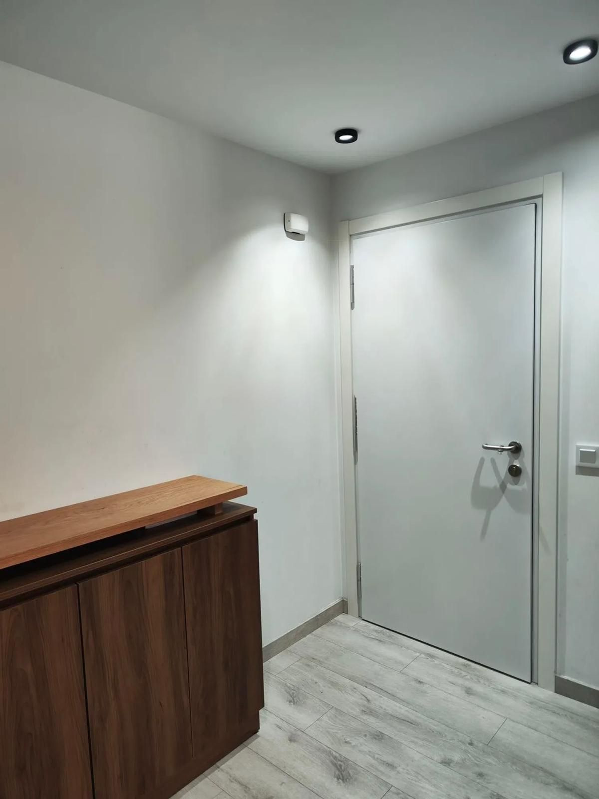 Moderne entree met houten kast en witte deur