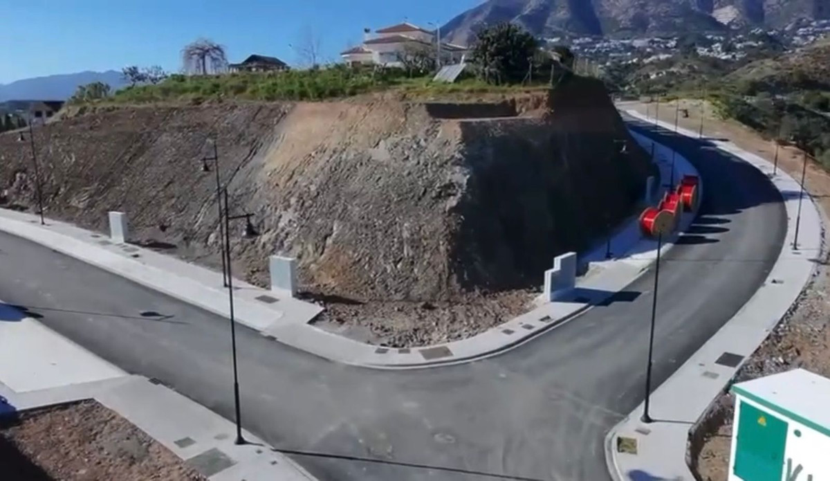 Overzicht van ontwikkelingsgrond met bochtige weg en uitzicht op de bergen.