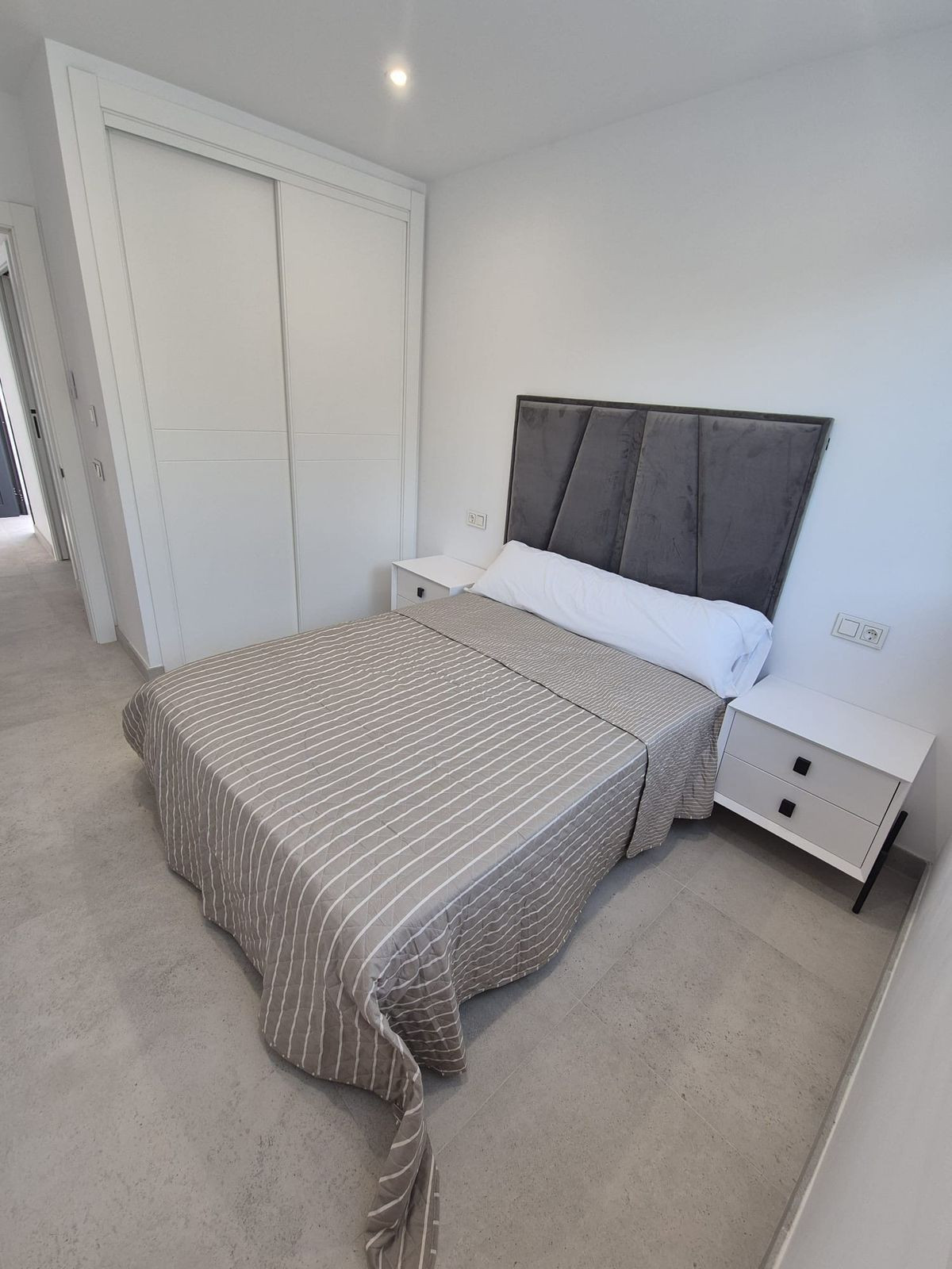 Moderne slaapkamer met grijze accenten, bed, nachtkastjes en schuifdeurkast