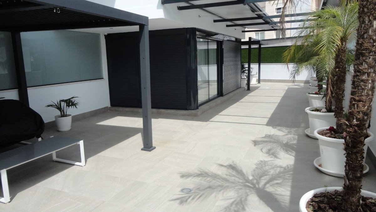 Spacious modern terrace with palm trees in pots, a lounge chair, and covered seating area.