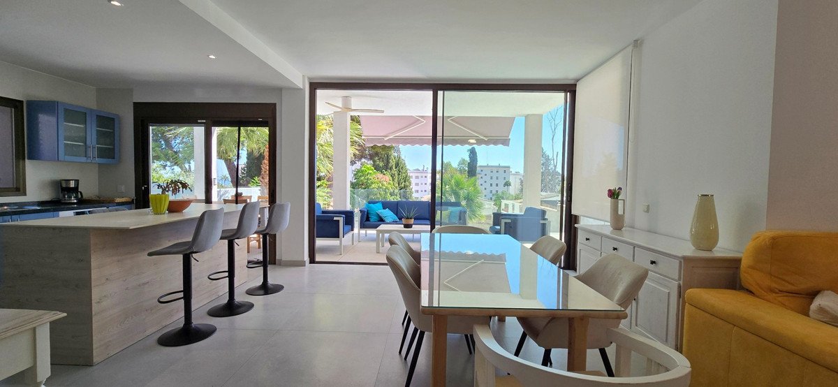 Spacious open-plan living, dining, and kitchen area with a large terrace accessible through sliding glass doors, offering a bright and outdoor seating area.