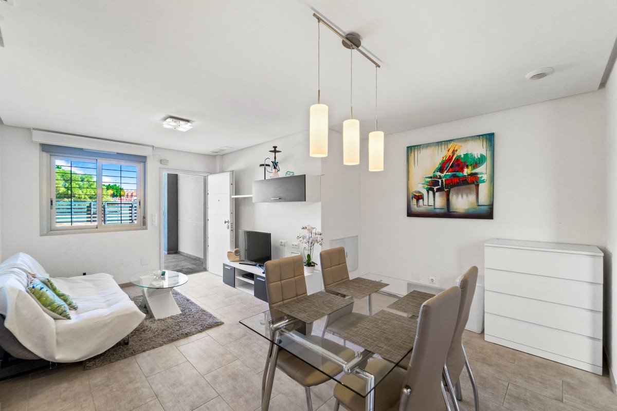 Modern living and dining area with glass table, comfortable sofa, large window, and a piano painting on the wall.
