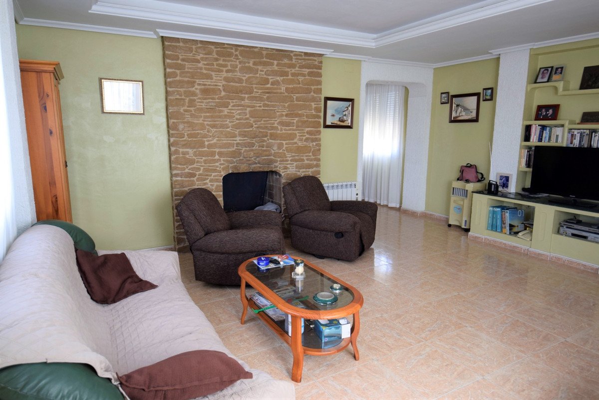 Comfortable living room with two armchairs, a sofa, a stone fireplace, and a TV unit with shelves.