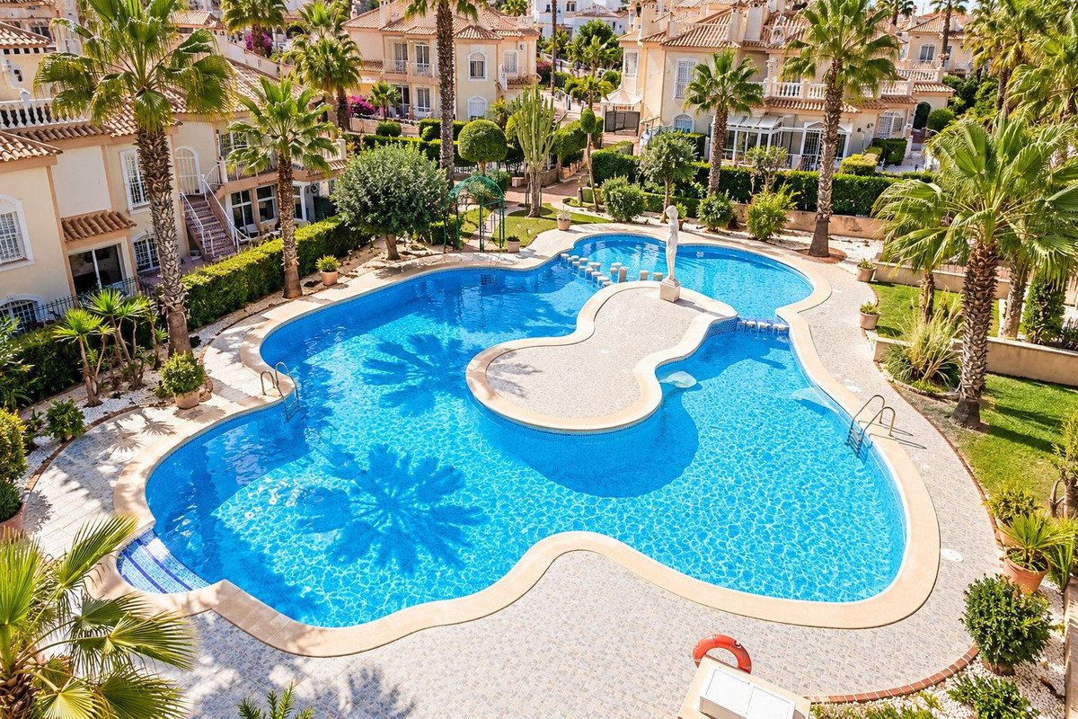 Luxurious resort-style swimming pool with palm trees, surrounded by residential buildings and manicured gardens.
