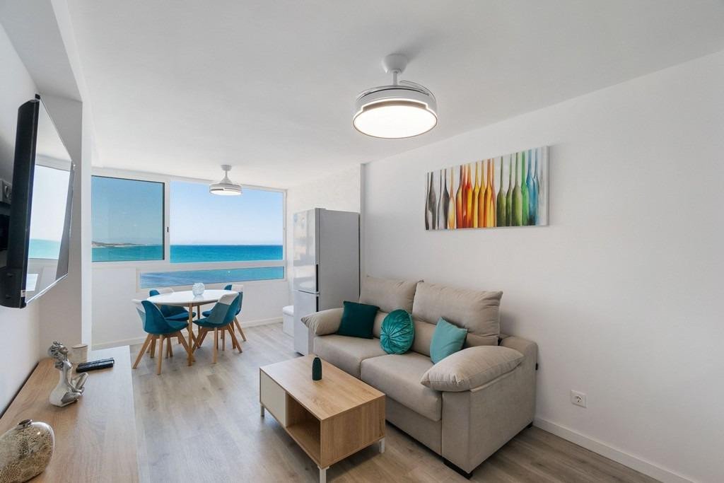 Modern living and dining area with a sofa, coffee table, and a large window offering a stunning sea view.
