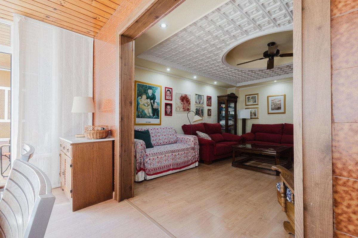 Interior view of a living room with red sofas, a patterned sofa, a decorative ceiling, and a ceiling fan.