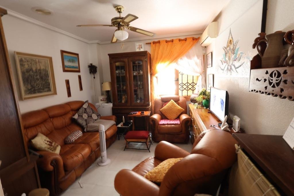 Cozy living room with brown leather sofas, a wooden cabinet, television, and a ceiling fan.