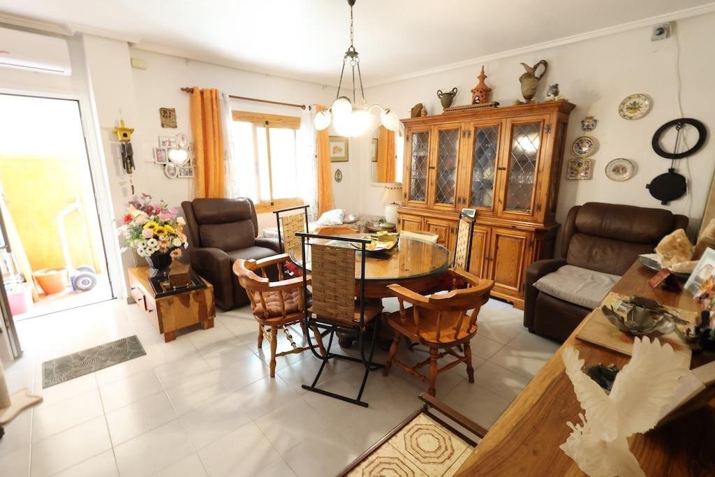 A dining room with a wooden table, chairs, and a large cabinet, featuring comfortable seating and a view towards the outdoors.