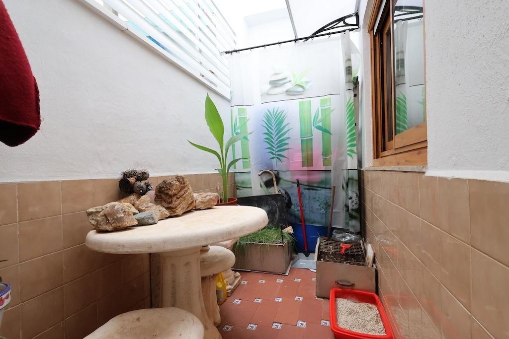 An outdoor space with a stone table, plants, a shower curtain with a bamboo print, and a grill.