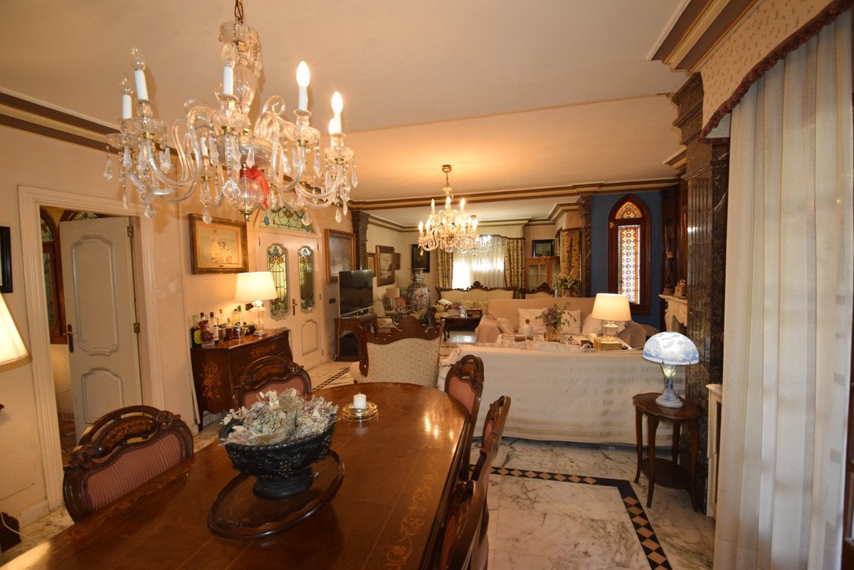 Elegant living room with chandeliers, dining table, and plush seating