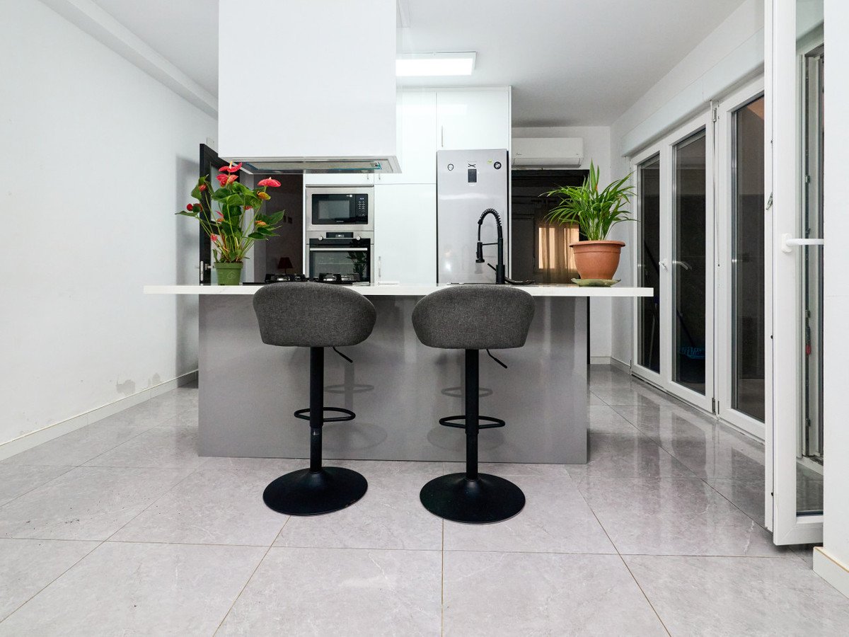 Modern kitchen with island, stools, plants, and sliding glass doors