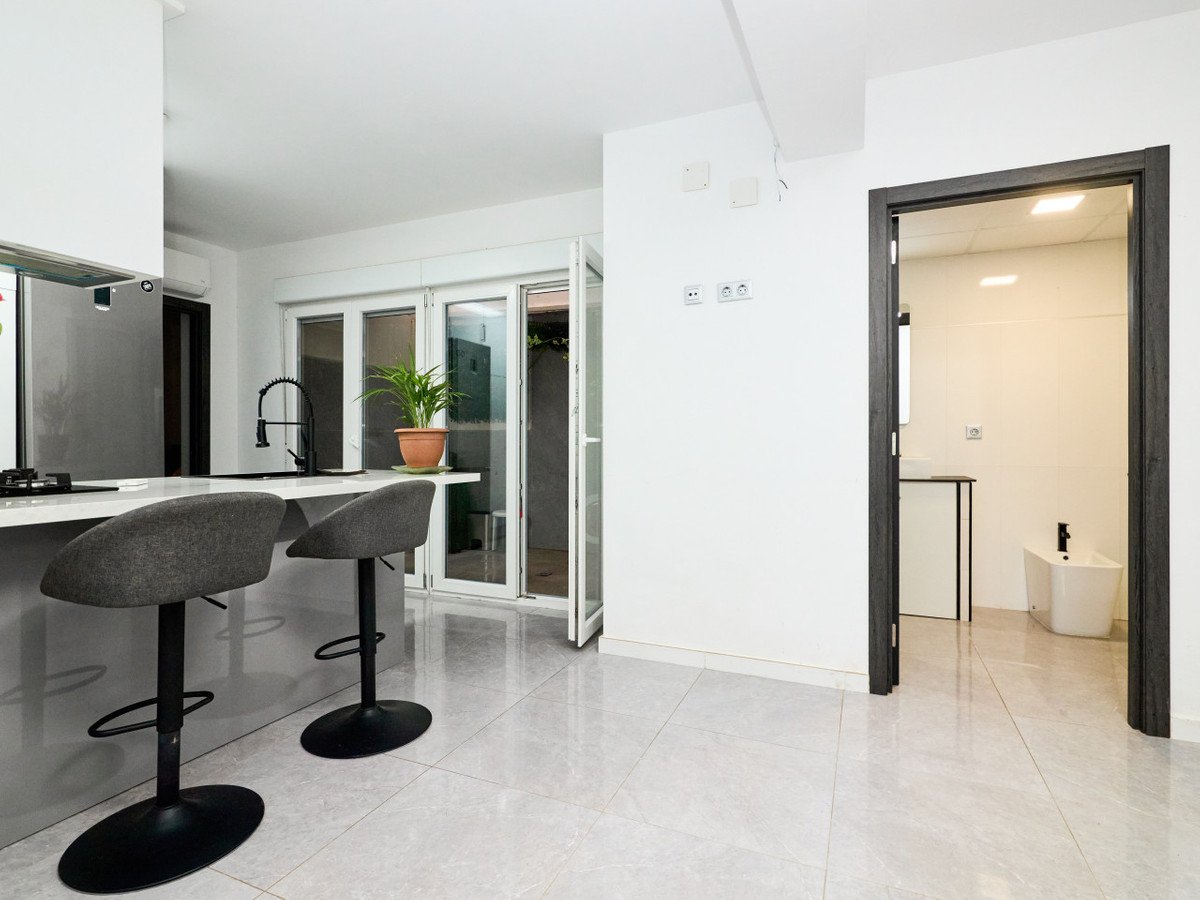 Modern kitchen with bar stools, sliding glass doors, and adjacent bathroom