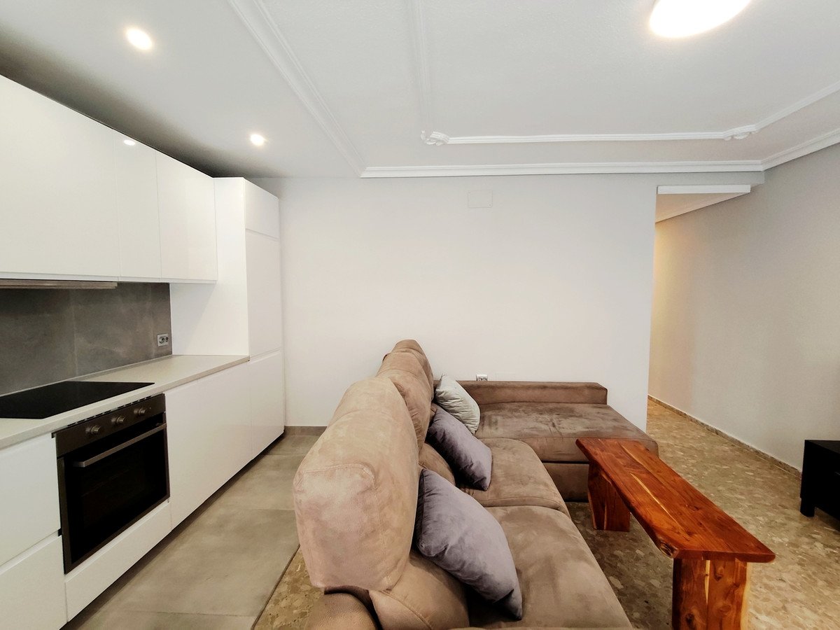 A modern living area with a sectional sofa, contemporary kitchen, and a rustic wooden coffee table.