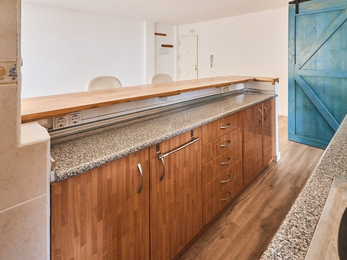 Modern kitchen breakfast bar with wooden countertop and cabinets, granite, and a blue sliding barn door.