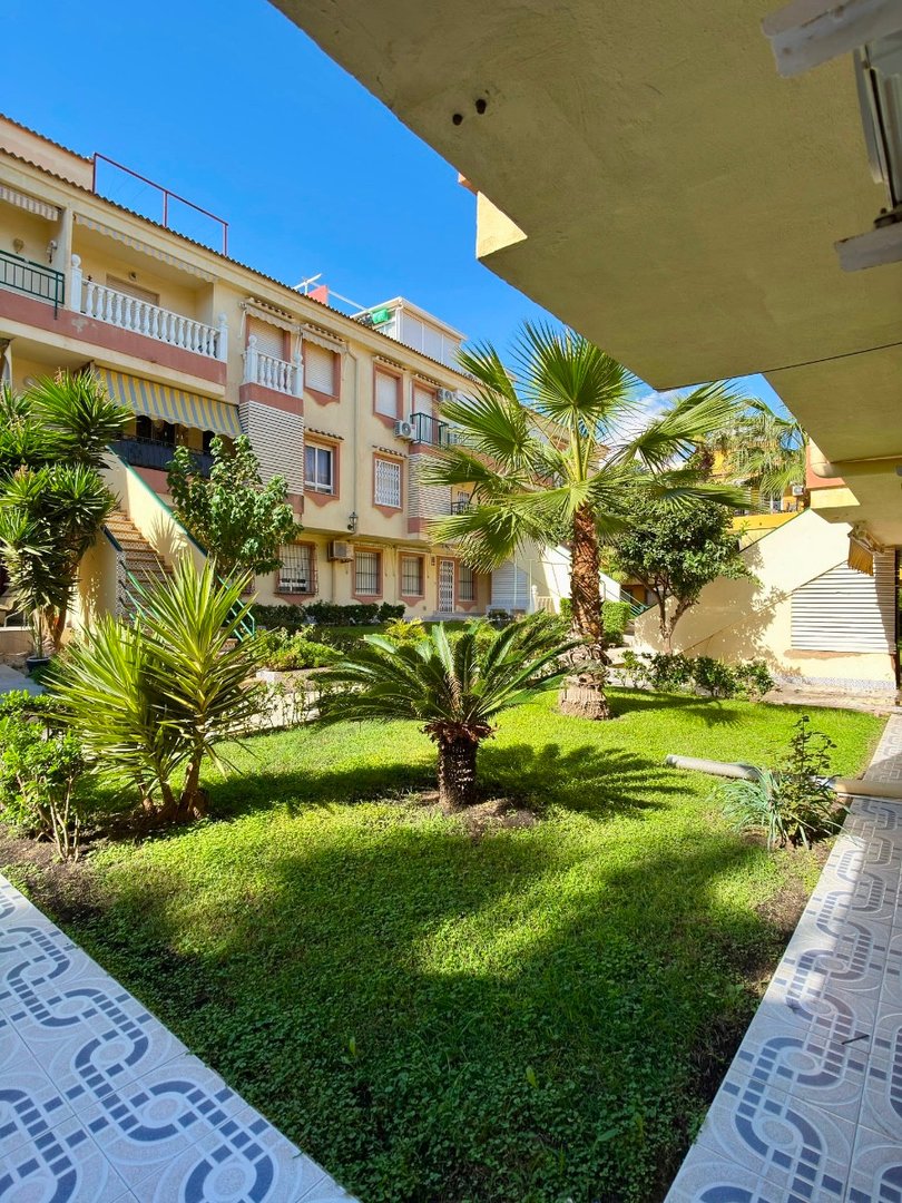 Apartment complex with a well-maintained garden and palm trees
