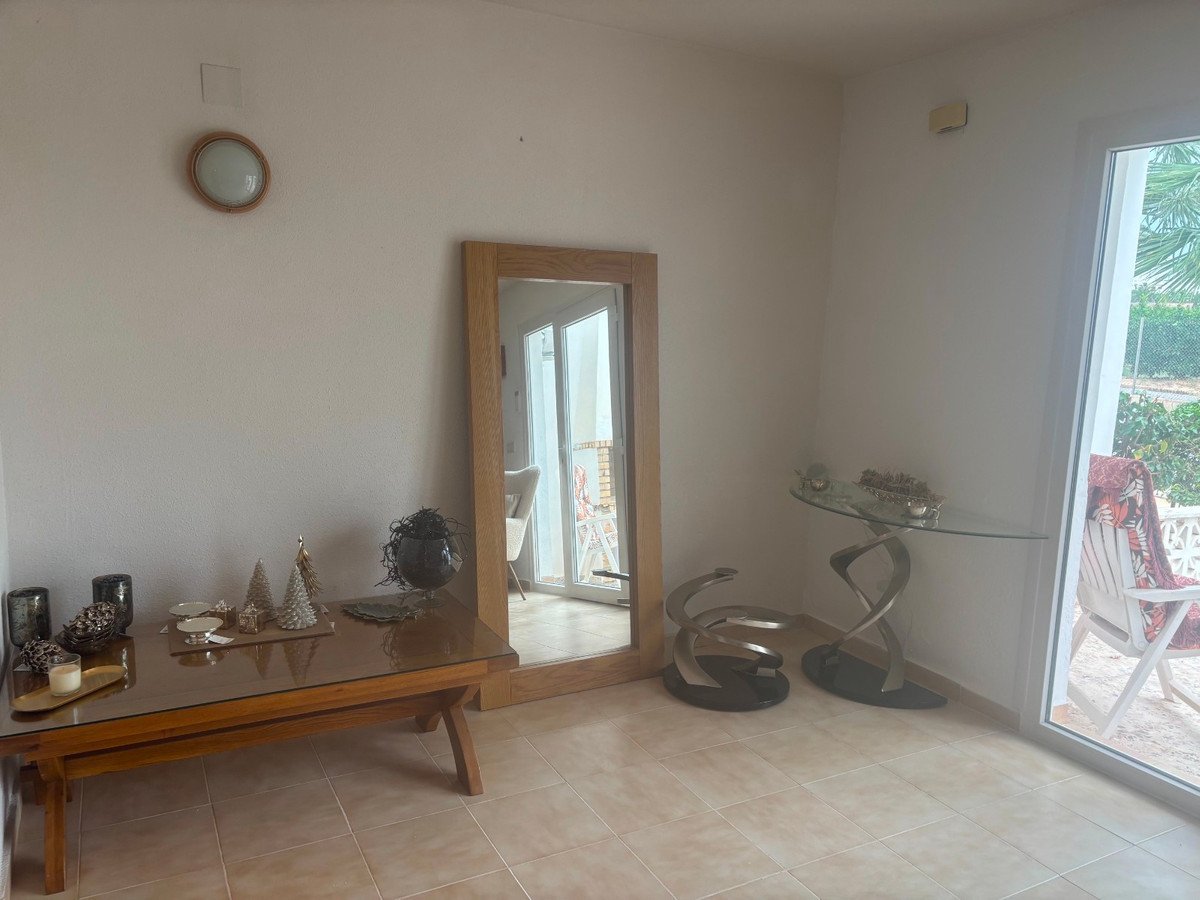 Interior view of a room with a large mirror, coffee table, console table, and a patio door leading outdoors.