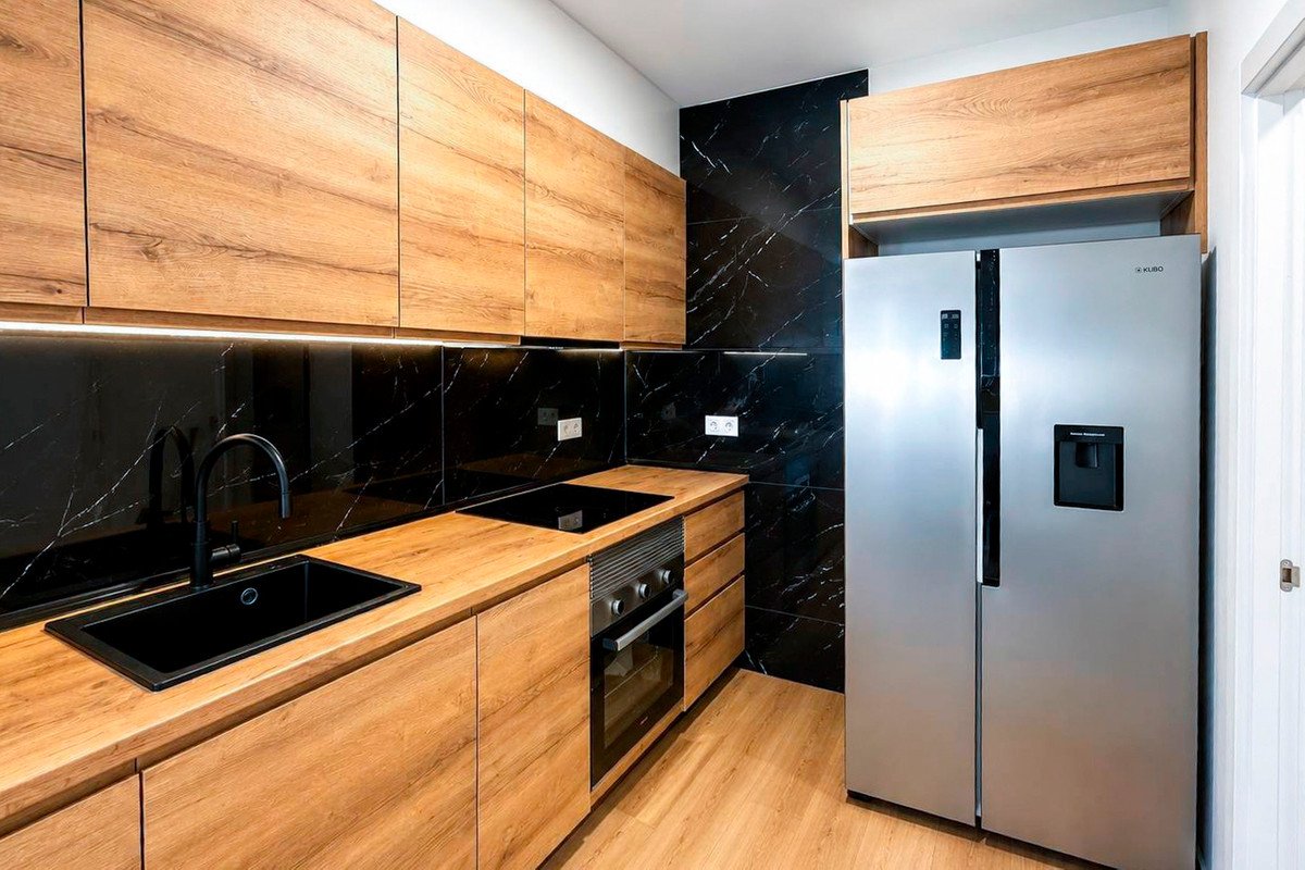 Modern kitchen with wooden cabinets, black marble backsplash, and stainless steel appliances