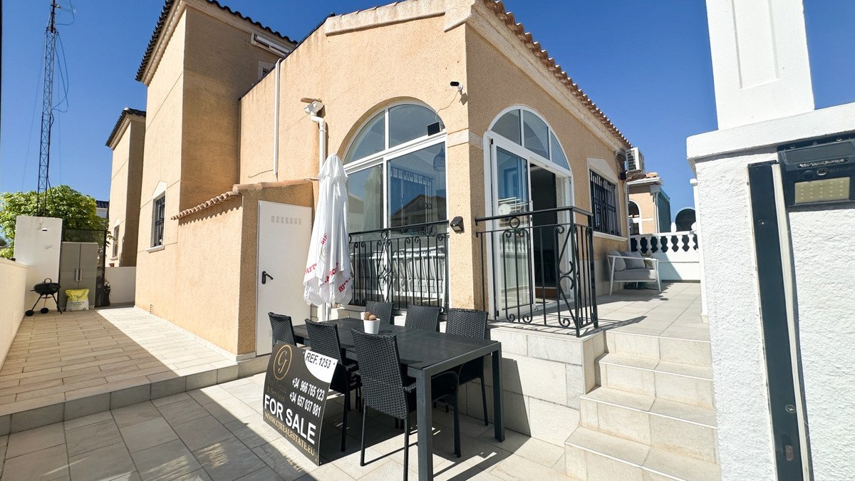Terrace with dining table and chairs, barbecue, and outdoor seating area, featuring large arched windows and balcony.