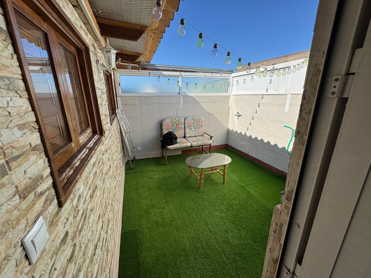 A cozy terrace with artificial grass, seating, and string lights, perfect for relaxing outdoors.