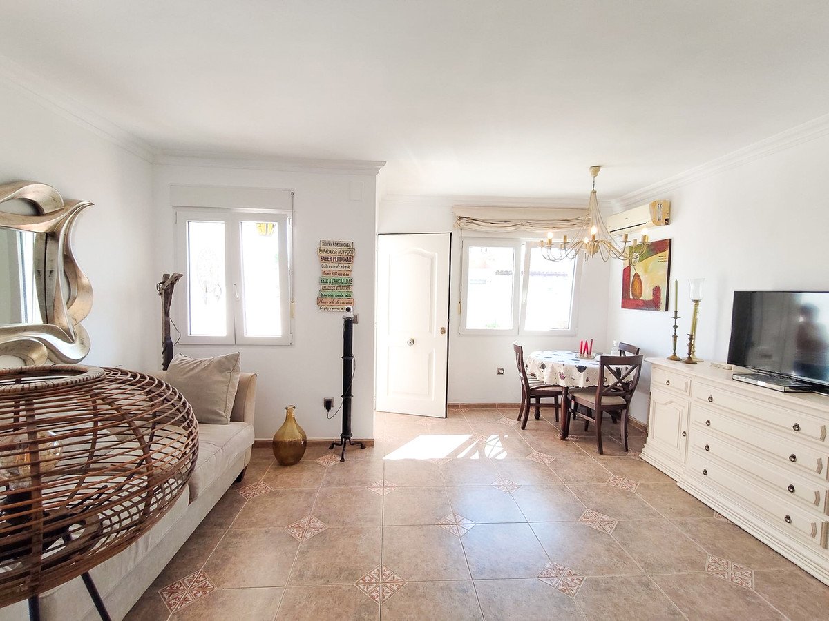 Bright living and dining room with a sofa, dining table, TV, and large windows.