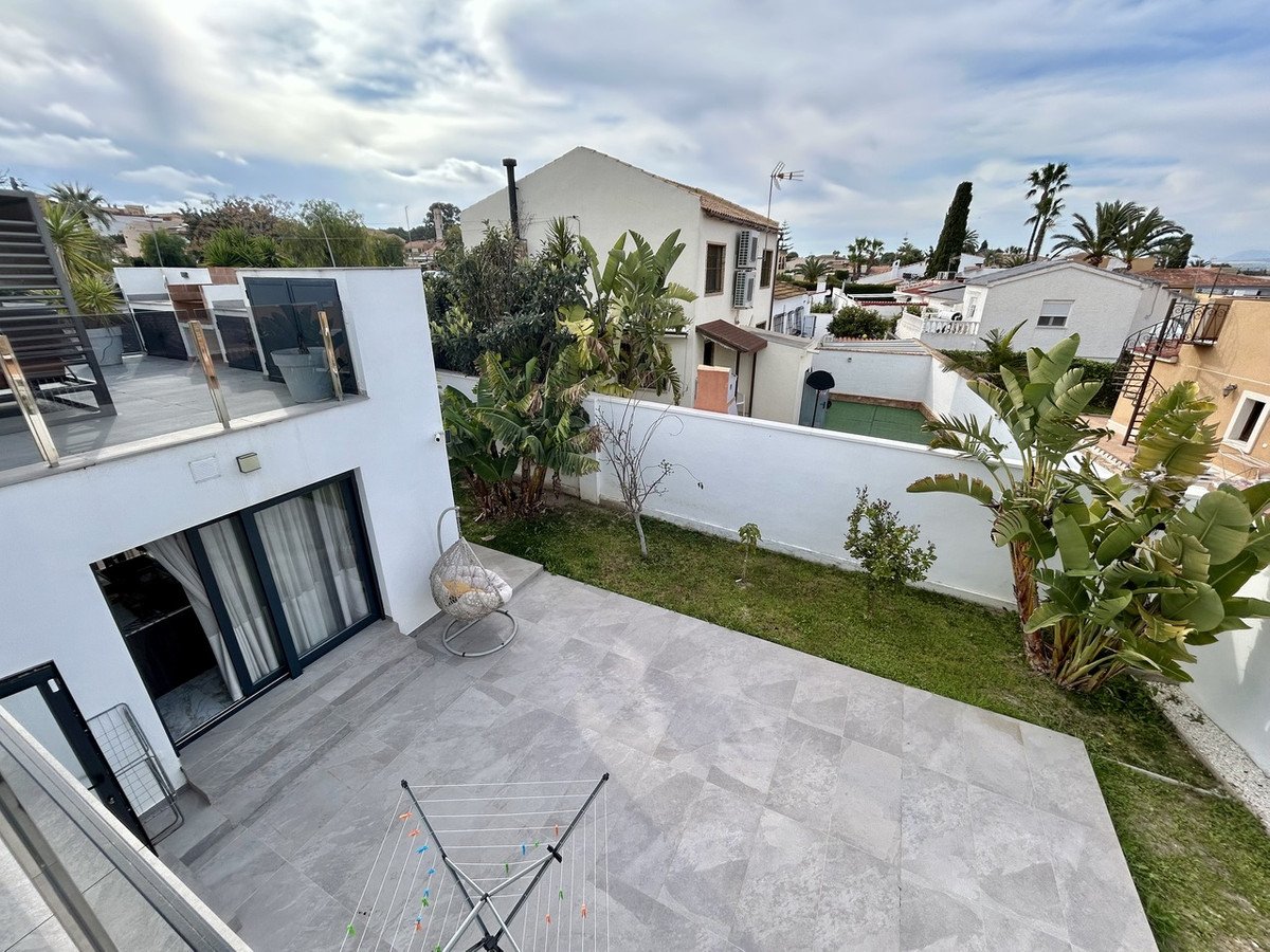 Modern rooftop garden with plants and outdoor furniture overlooking a residential area