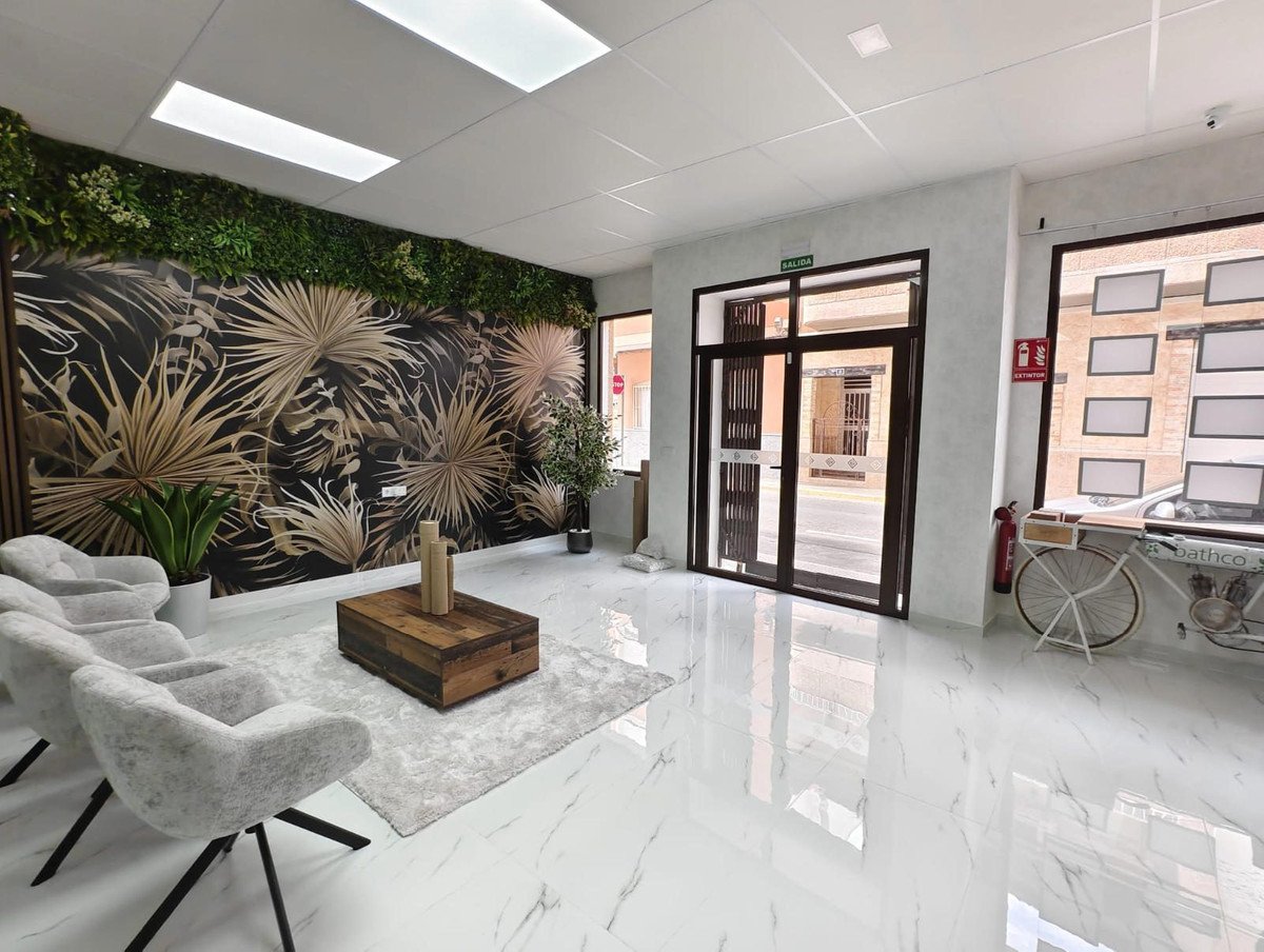 Modern waiting area with tropical wallpaper, comfortable seating, and a wooden coffee table.