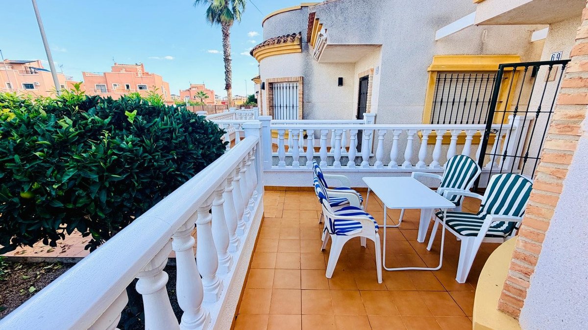 Outdoor terrace with table, striped chairs, and palm tree view