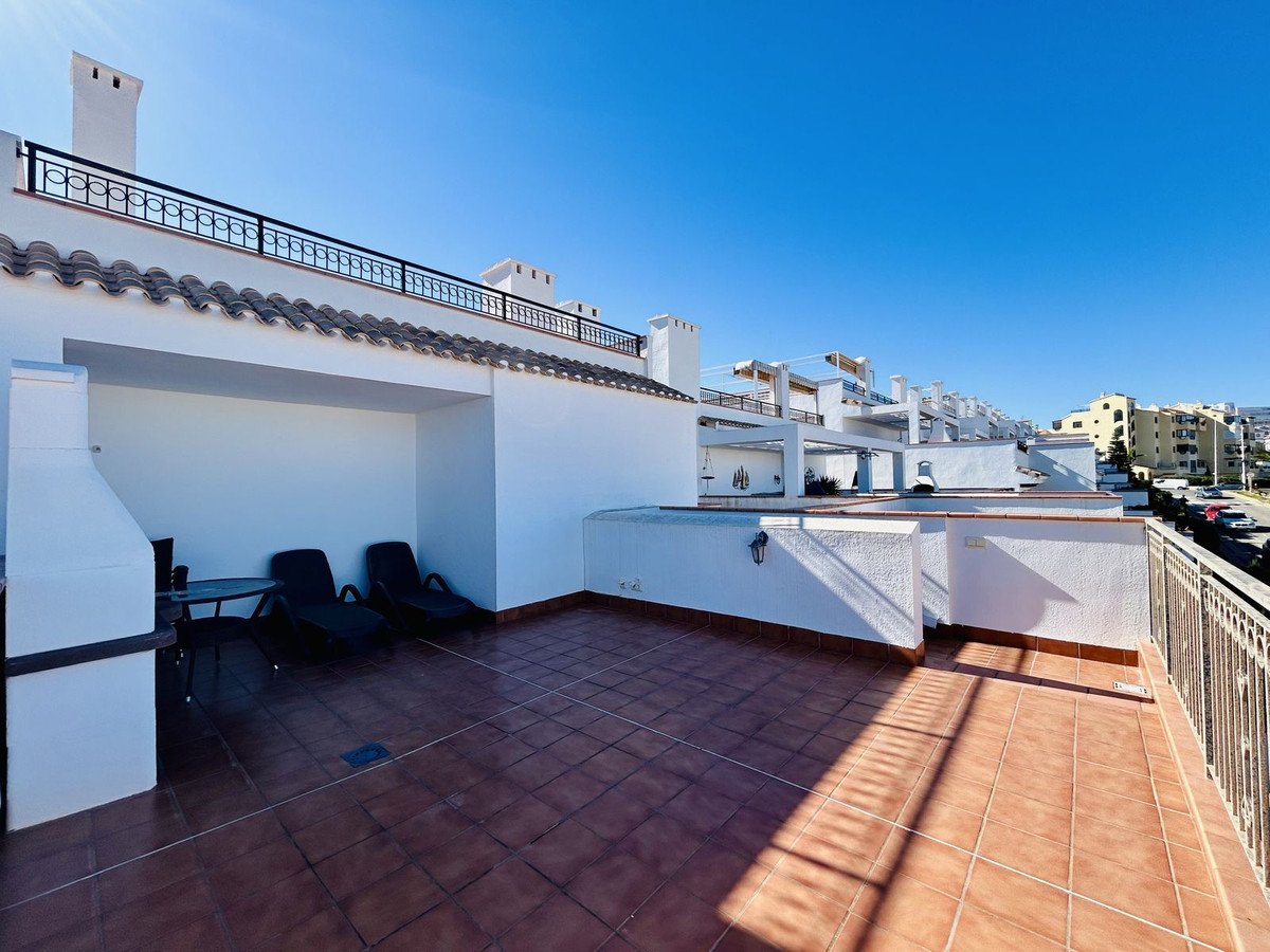 Spacious rooftop terrace with barbecue, loungers, and a table, offering sea and town views under a clear blue sky.