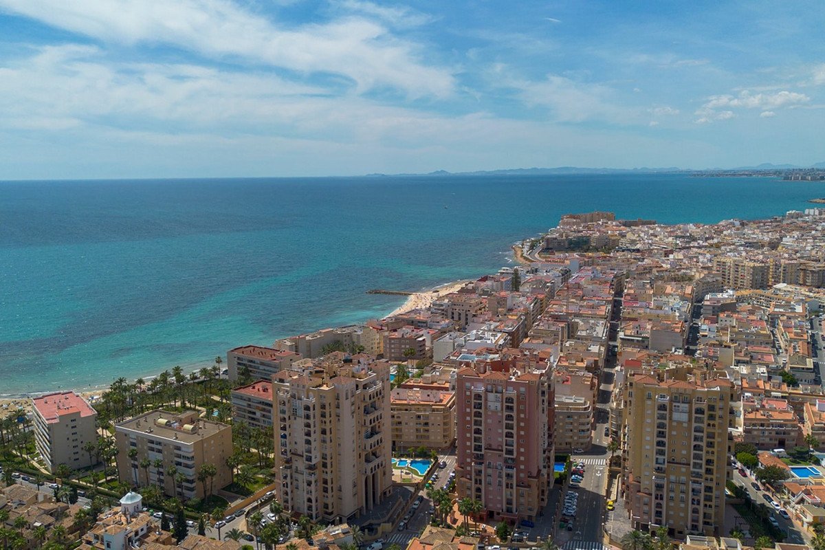 Aerial view of coastal city with sea, buildings, and beach.