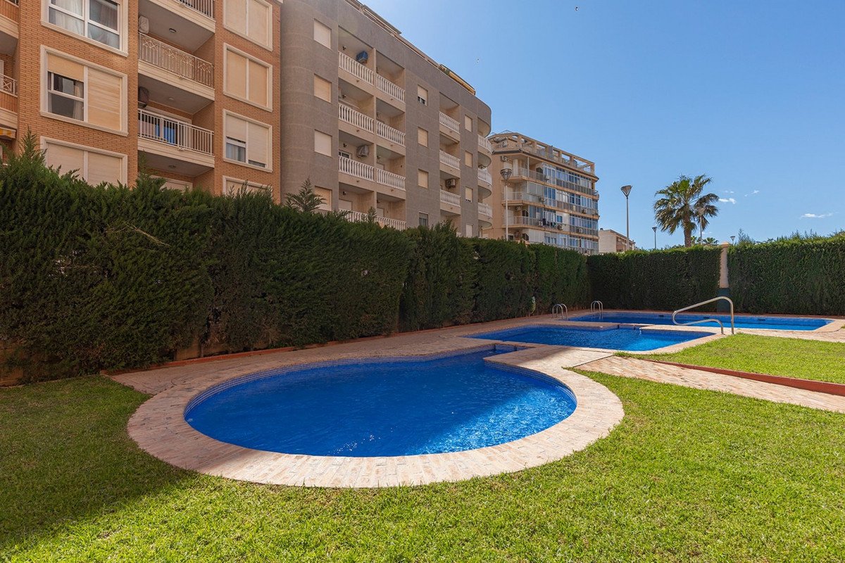 Outdoor swimming pools in apartment complex with green lawns and hedges