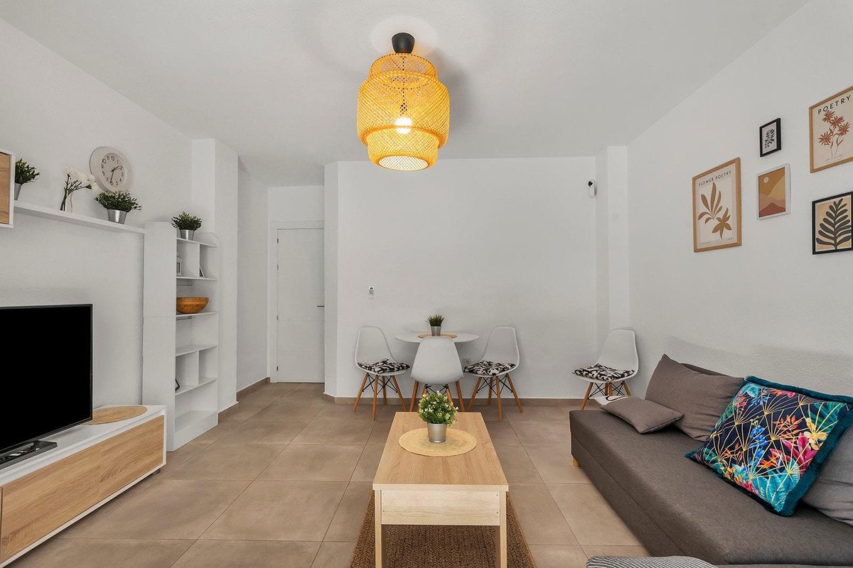 Modern living and dining area with sofa, coffee table, dining set, and TV, decorated with artwork.