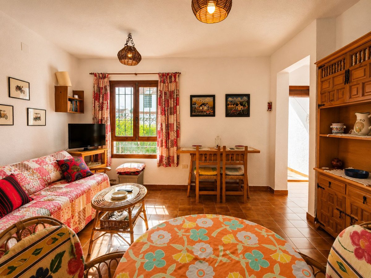 Cozy living and dining room with floral sofa, wooden furniture, and bright window view.