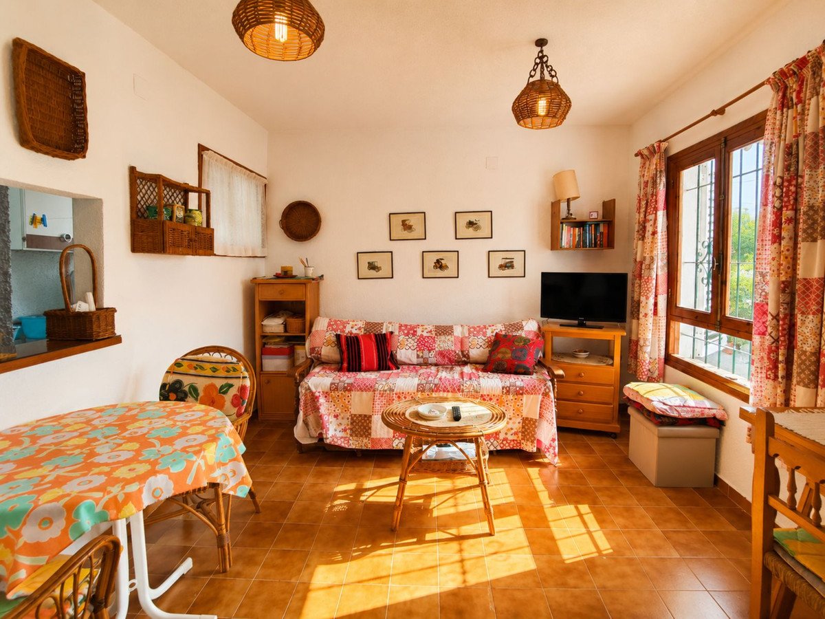 Bright living room with patterned sofa, wooden furniture, and large window with curtains