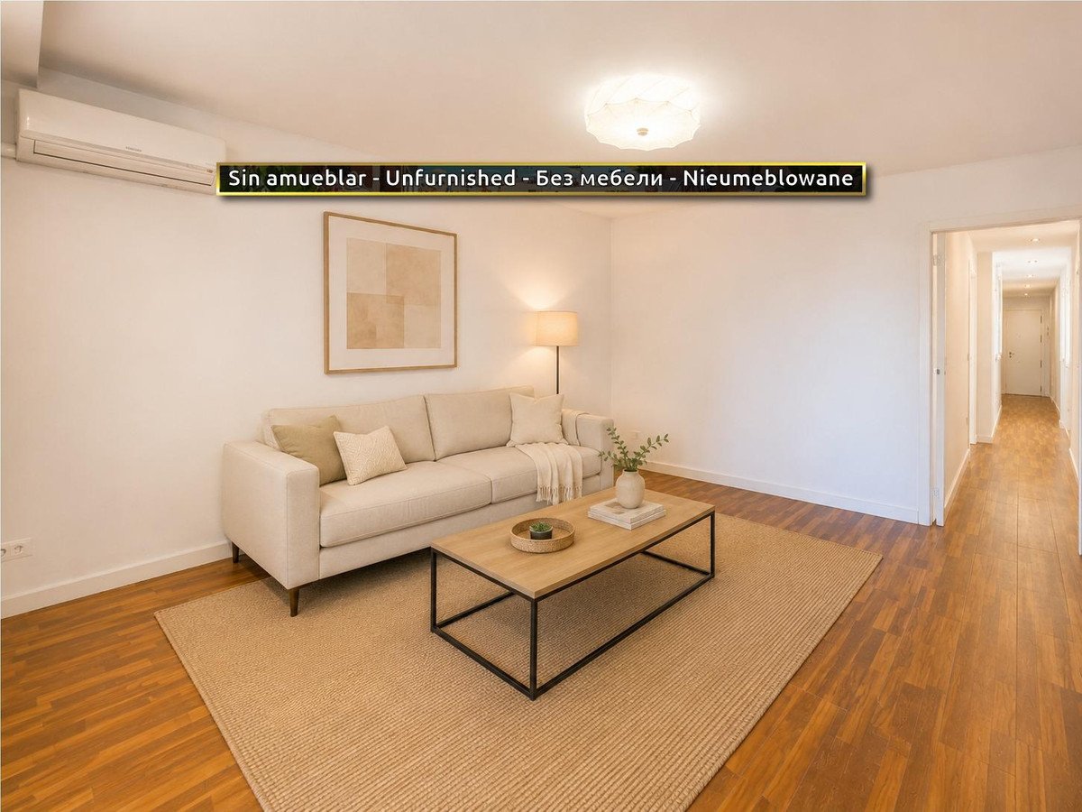 Unfurnished living room with a beige sofa, a coffee table on a rug, and a hallway in the background.