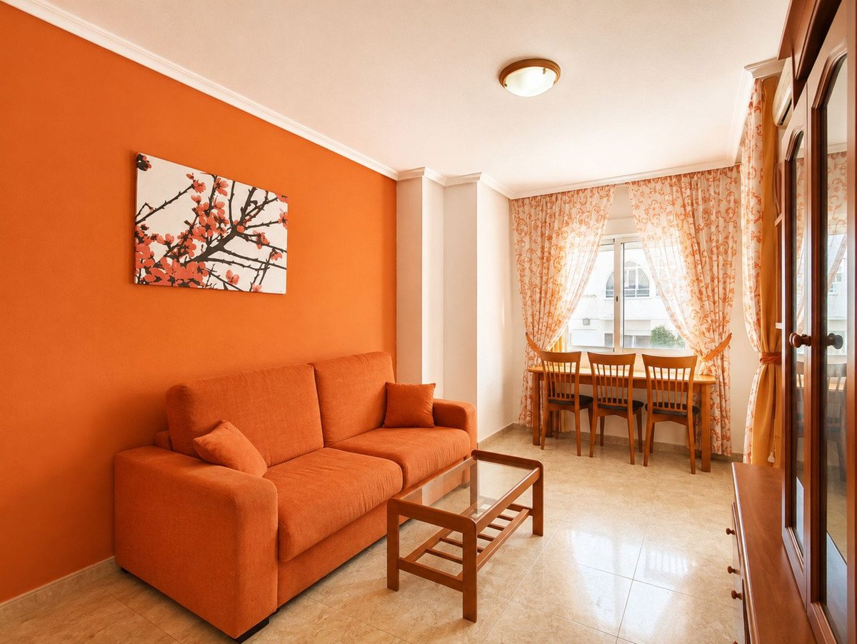 Orange living room with sofa, coffee table, and dining area near window