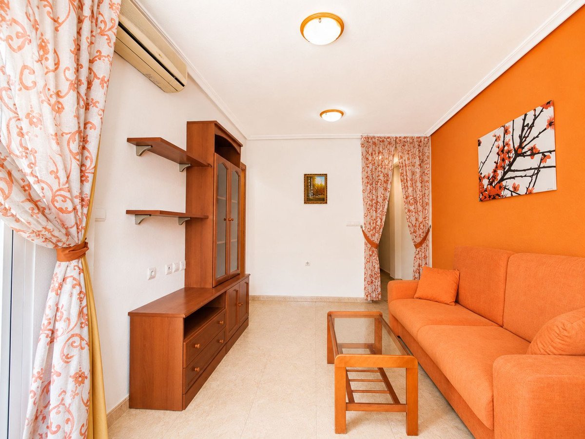 Orange living room with sofa, wooden shelves, and floral curtains