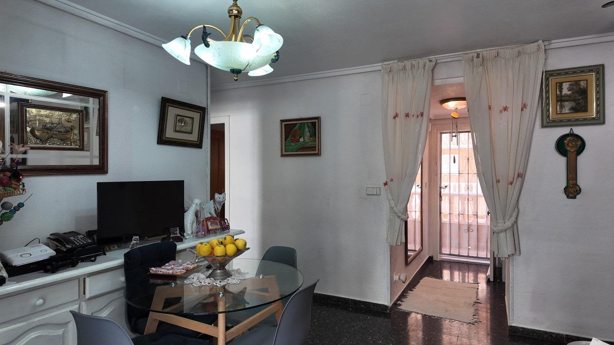 Dining and living room with glass table, TV, and outdoor view through curtains
