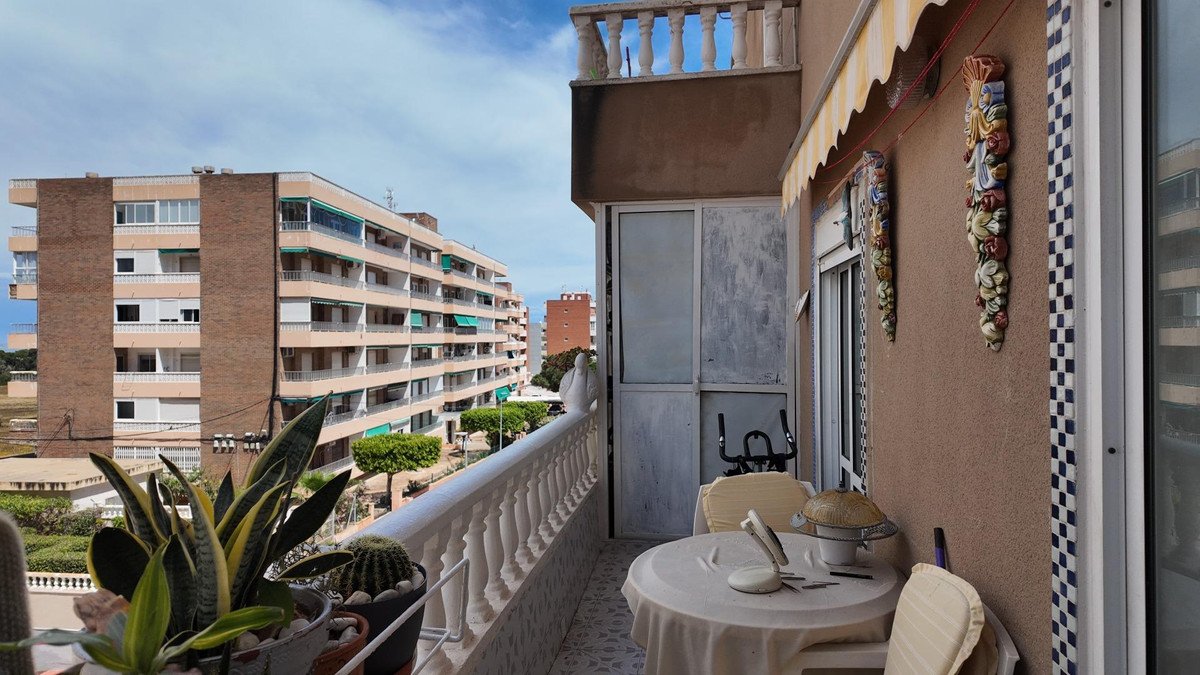 Balcony with table, chairs, plants, and city buildings view